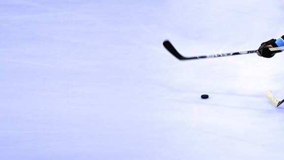 Ice hockey players competing for the puck on an ice rink.