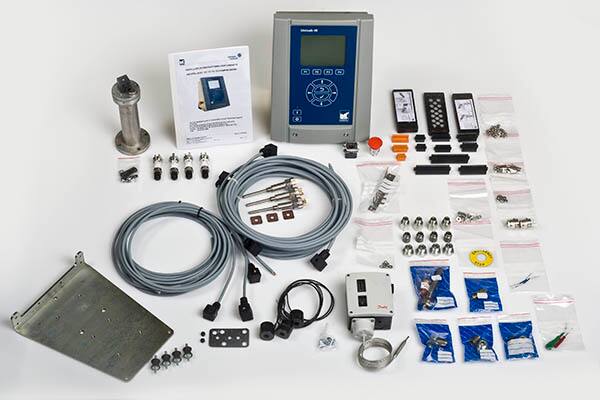 Industrial control system retrofit kit with controller, cables, sensors, and installation components arranged on a table.