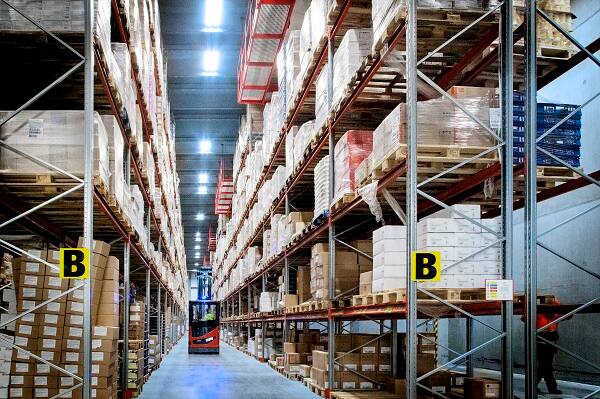 Warehouse aisle with pallet racks and stored goods.